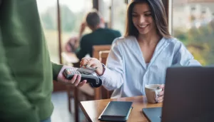 Businesswoman Making Credit Card Payment While Working In Cafe