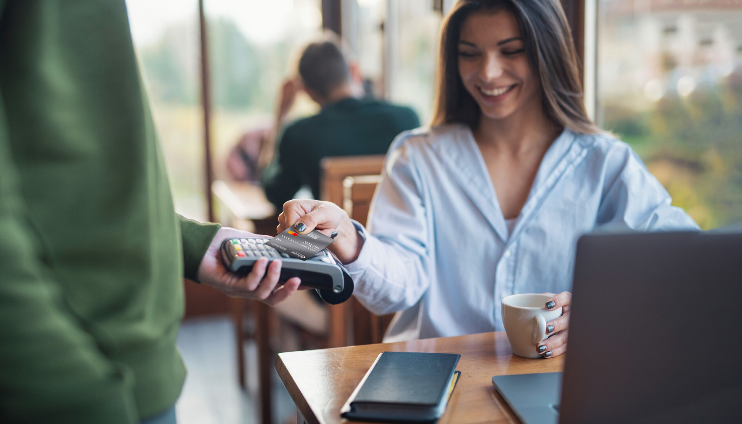 Businesswoman Making Credit Card Payment While Working In Cafe